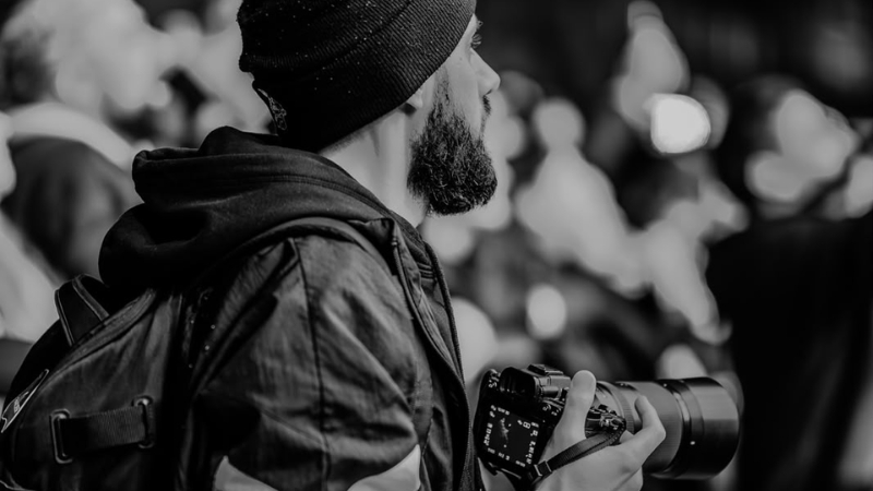 Hombre mirando de perfil con una c&aacute;mara fotogr&aacute;fica en las manos.